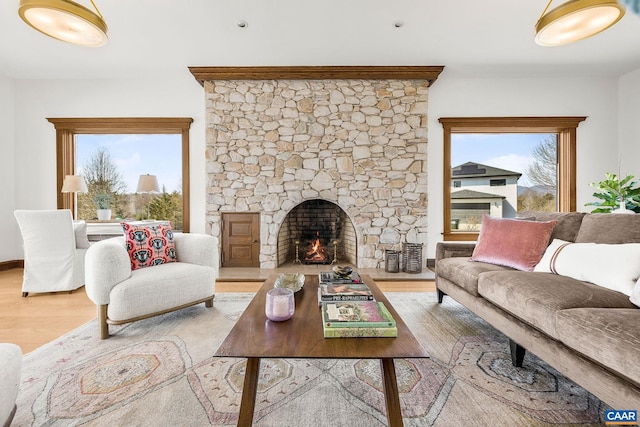 living room with light wood-style floors and a stone fireplace