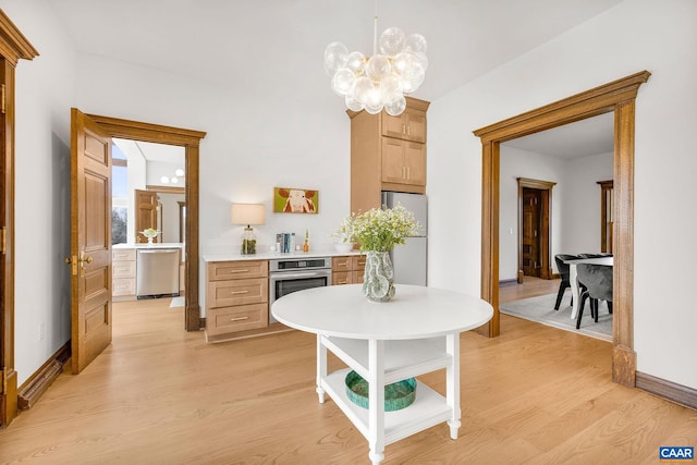 kitchen with baseboards, light wood-type flooring, light countertops, a notable chandelier, and stainless steel appliances