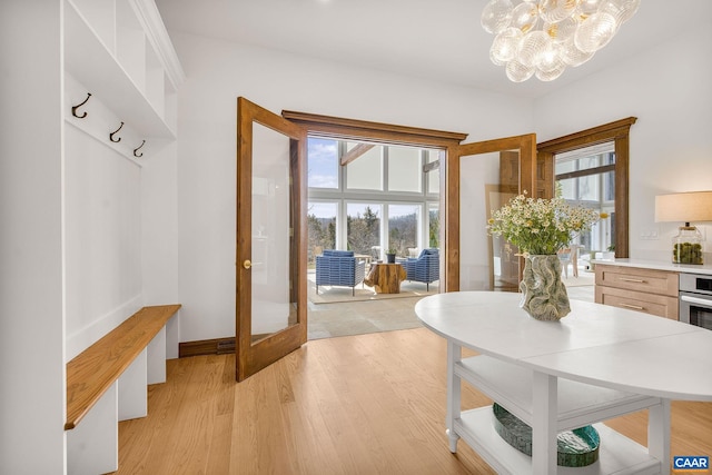 dining space with a notable chandelier, baseboards, light wood-type flooring, and a wealth of natural light