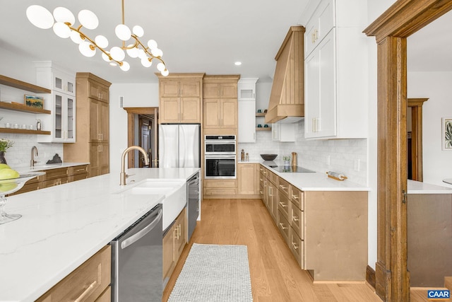 kitchen featuring open shelves, light wood-type flooring, appliances with stainless steel finishes, and a sink