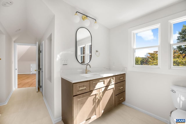 bathroom with toilet, vanity, and baseboards