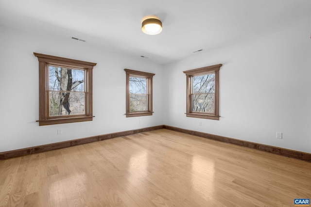 empty room with visible vents, baseboards, and light wood finished floors