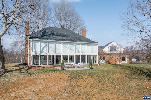 rear view of property featuring brick siding, a lawn, a chimney, and a patio