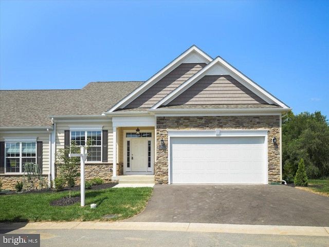 craftsman-style house with an attached garage, stone siding, and driveway