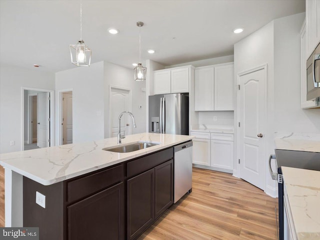 kitchen with dark brown cabinetry, light wood-type flooring, appliances with stainless steel finishes, white cabinetry, and a sink