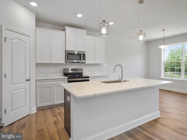 kitchen with light wood-type flooring, pendant lighting, a sink, white cabinetry, and stainless steel appliances