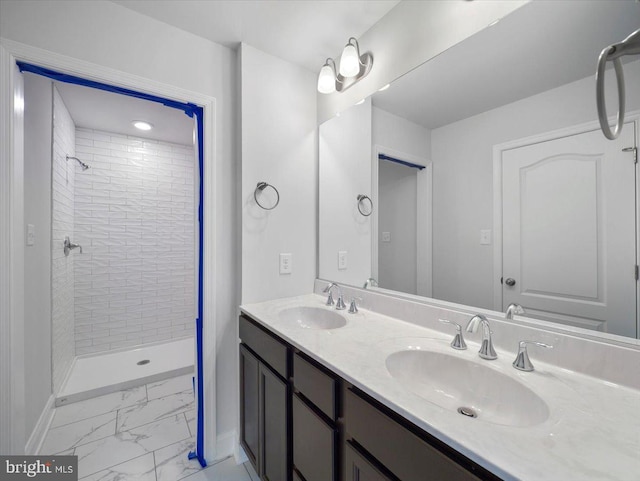 full bathroom featuring baseboards, marble finish floor, a tile shower, and a sink