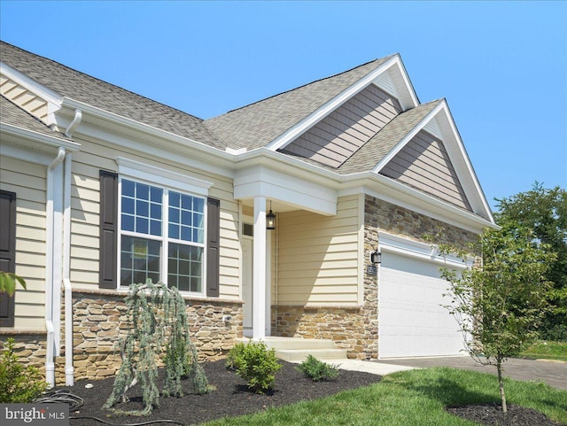 view of front of home featuring a garage, stone siding, and roof with shingles