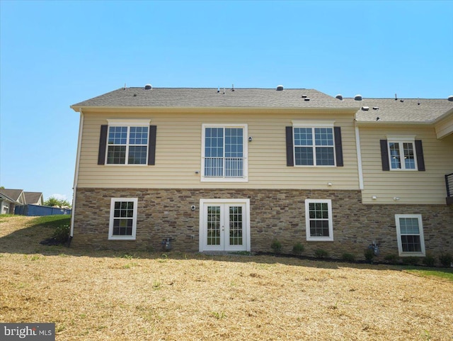 rear view of property with stone siding, french doors, and a yard