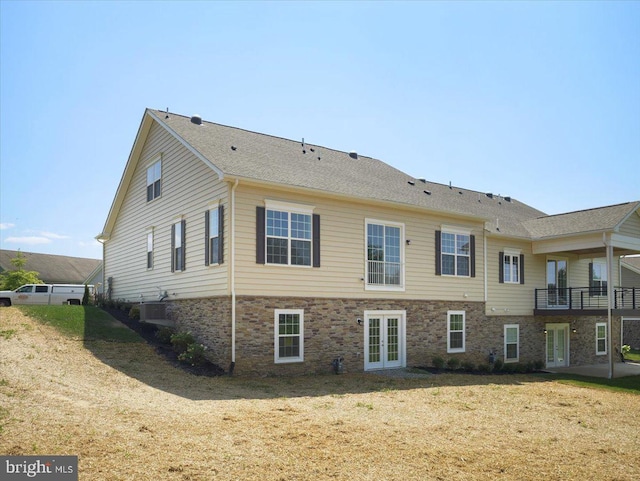 back of house featuring a patio, central AC unit, a yard, french doors, and stone siding