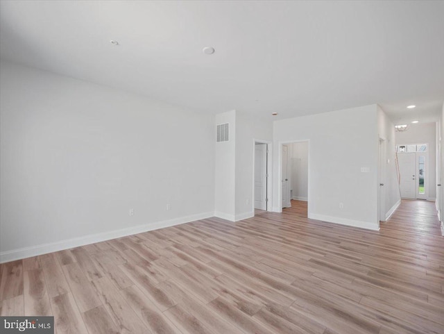 unfurnished living room with light wood finished floors, visible vents, and baseboards