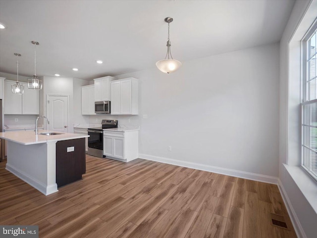 kitchen with a sink, appliances with stainless steel finishes, light wood-style flooring, and light countertops