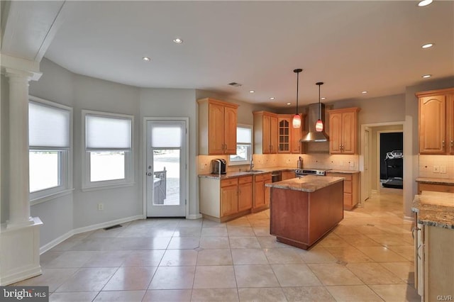 kitchen featuring wall chimney exhaust hood, visible vents, a kitchen island, and decorative columns