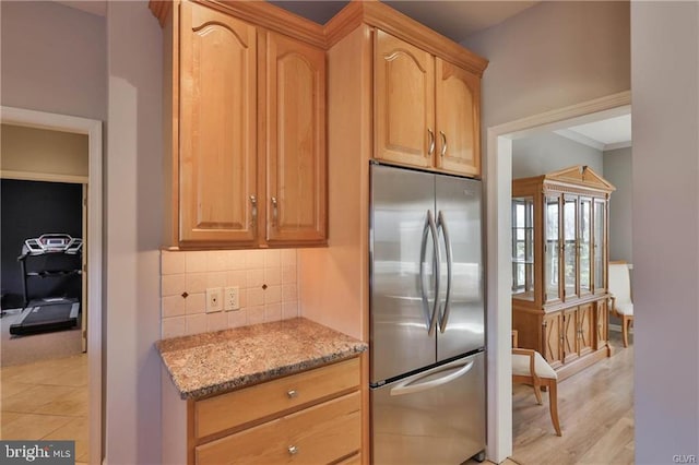 kitchen featuring stainless steel refrigerator, decorative backsplash, and light stone countertops