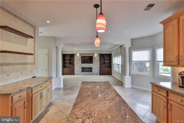 kitchen with decorative columns, light stone countertops, visible vents, and a wealth of natural light