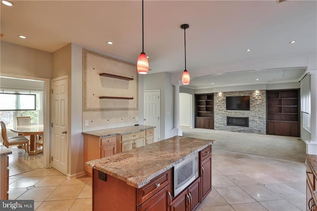 kitchen featuring stainless steel microwave, light stone countertops, decorative light fixtures, light tile patterned floors, and recessed lighting