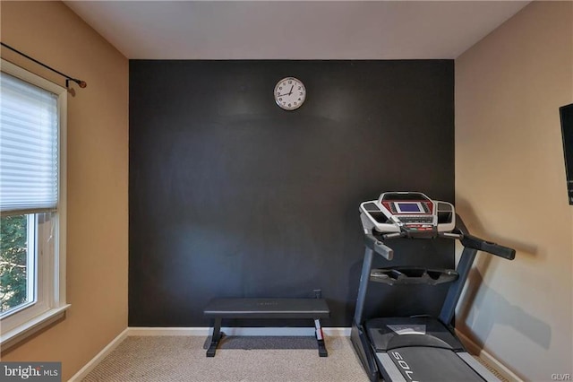 workout area with an accent wall, baseboards, and carpet floors