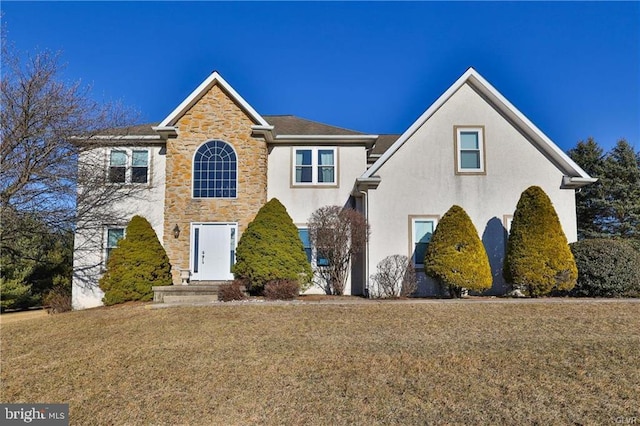 view of front of house featuring a front lawn, stone siding, and stucco siding