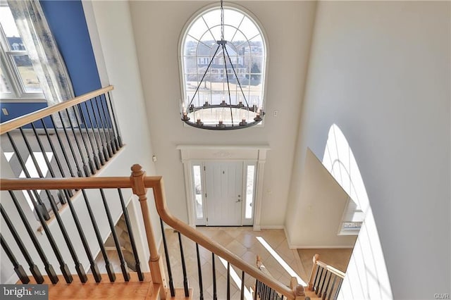 foyer entrance featuring a notable chandelier, baseboards, stairs, and a towering ceiling