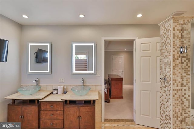 full bathroom with double vanity, recessed lighting, tiled shower, and a sink