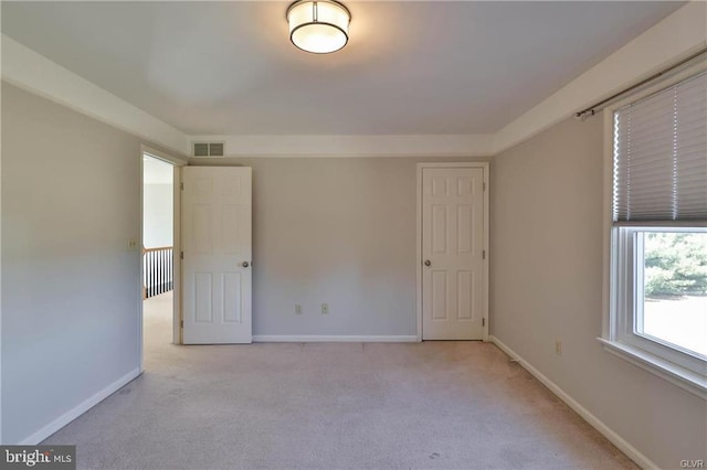 spare room featuring visible vents, light colored carpet, and baseboards