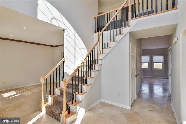 stairs featuring recessed lighting, baseboards, a high ceiling, and crown molding