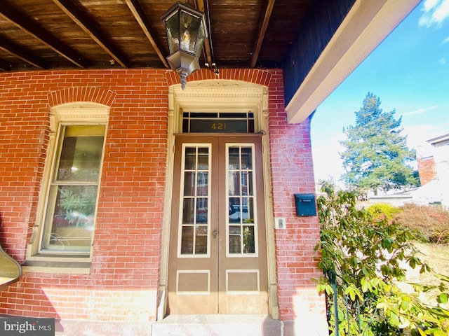 view of exterior entry with brick siding and french doors