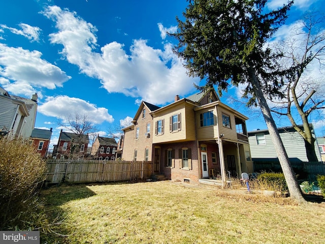 back of property featuring brick siding, a chimney, a lawn, and fence