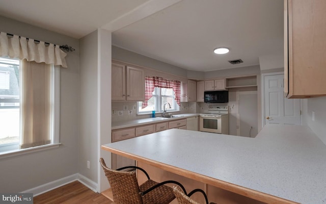 kitchen with visible vents, a sink, white electric stove, a peninsula, and black microwave