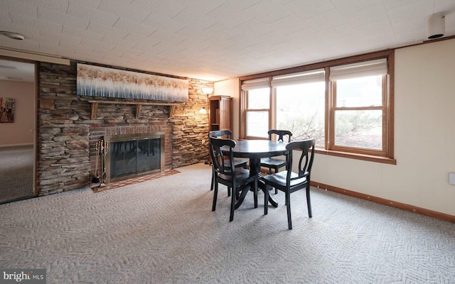 dining space featuring baseboards, carpet floors, and a fireplace