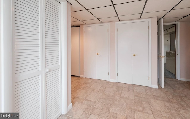 unfurnished bedroom featuring two closets and a paneled ceiling