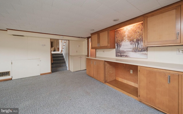 kitchen featuring brown cabinetry, carpet flooring, light countertops, and visible vents