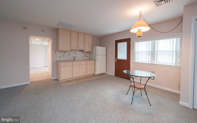 kitchen featuring visible vents, light colored carpet, light brown cabinets, and freestanding refrigerator