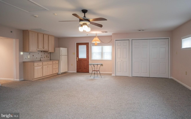 kitchen with light carpet, light brown cabinets, plenty of natural light, freestanding refrigerator, and ceiling fan