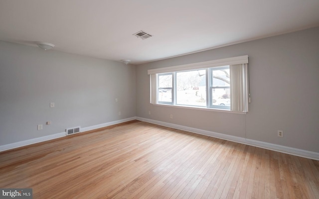 empty room featuring baseboards, visible vents, and light wood finished floors