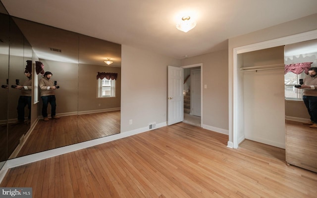 unfurnished bedroom featuring light wood finished floors, visible vents, a closet, and baseboards