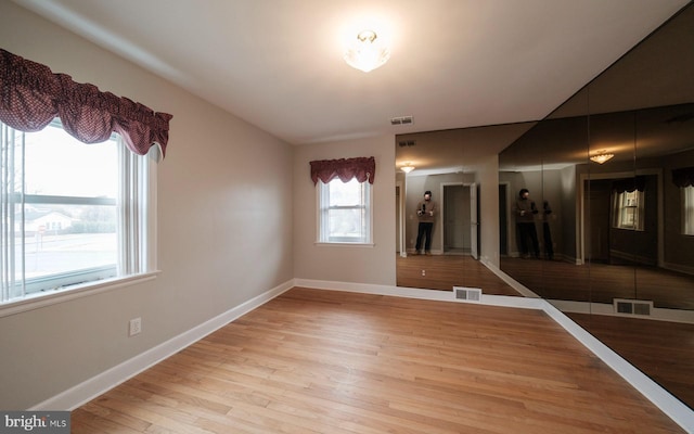 spare room with visible vents, light wood-type flooring, and baseboards