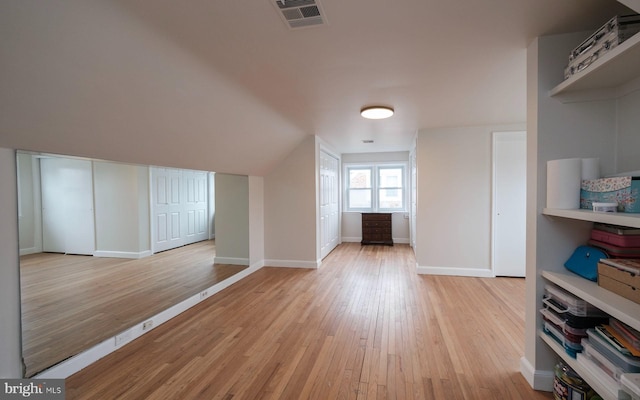 additional living space with visible vents, baseboards, vaulted ceiling, and light wood finished floors