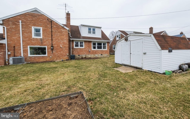 back of property featuring brick siding, central AC unit, a lawn, an outbuilding, and a storage unit