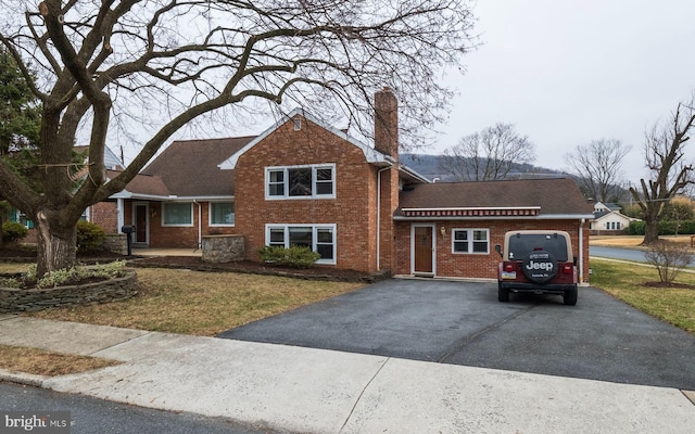 split level home featuring aphalt driveway, brick siding, and a front yard