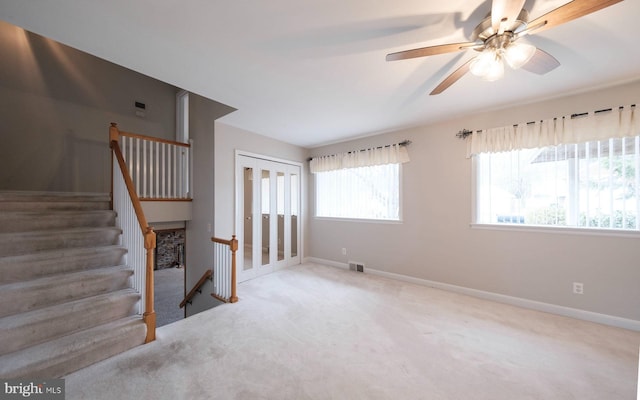 unfurnished living room with a ceiling fan, carpet, visible vents, and baseboards