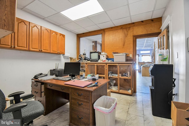 office featuring a drop ceiling, marble finish floor, and wood walls