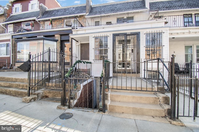 view of front of house with a gate, mansard roof, a shingled roof, and fence