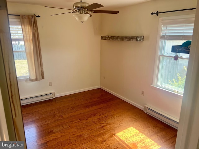 empty room featuring a baseboard radiator, baseboards, baseboard heating, and wood finished floors