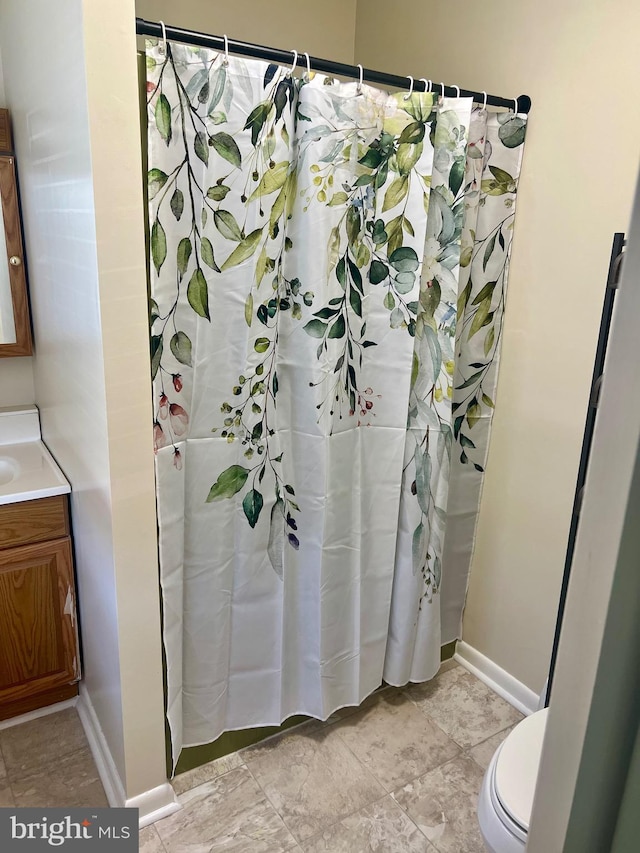 bathroom with vanity, curtained shower, toilet, and baseboards