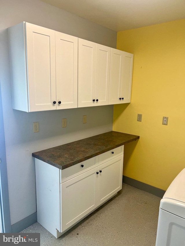 clothes washing area featuring washer / clothes dryer, cabinet space, and baseboards