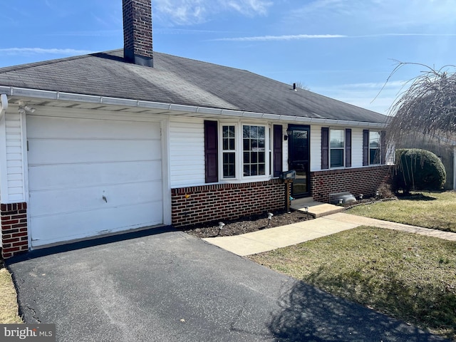 ranch-style home featuring brick siding, a shingled roof, aphalt driveway, a chimney, and an attached garage