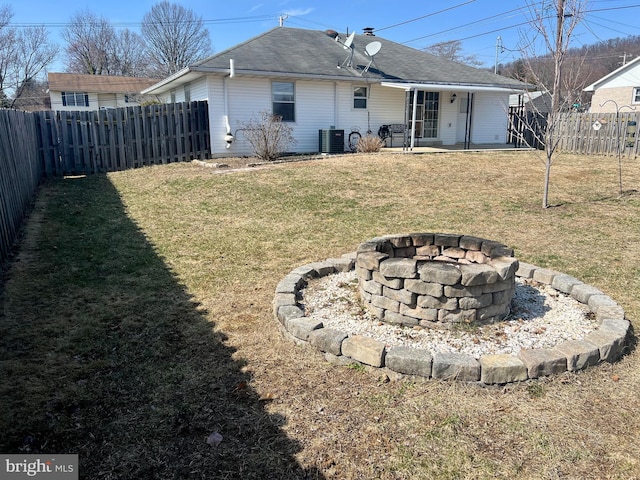 rear view of property with a fire pit, a lawn, and a fenced backyard