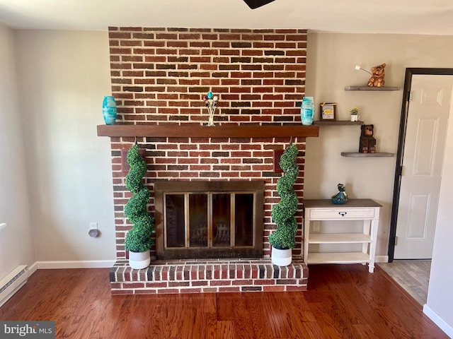 room details with a fireplace, a baseboard heating unit, baseboards, and wood finished floors