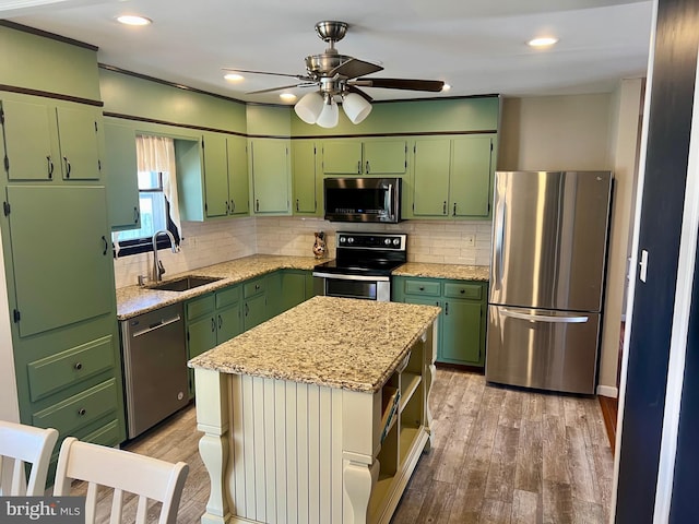 kitchen featuring a sink, stainless steel appliances, green cabinets, and light wood-style flooring